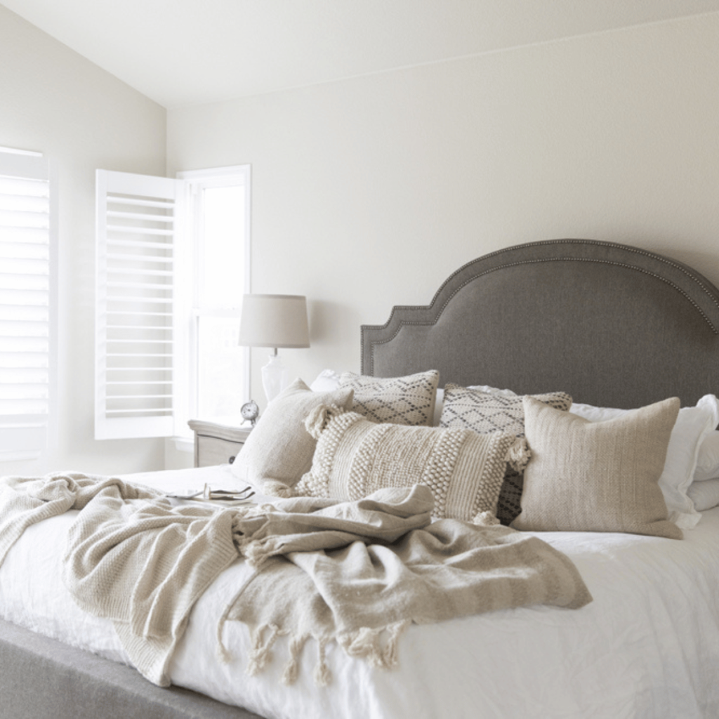 bedroom with neutral bedding and gray head board